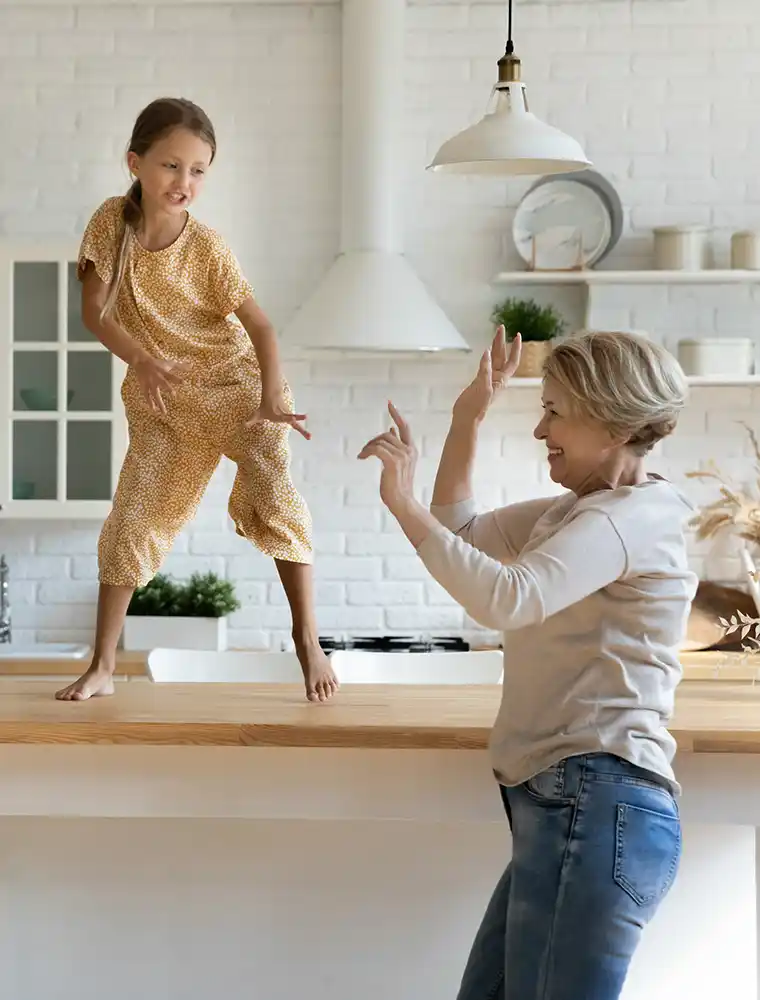 grandma and grandchild dance in modern kitchen