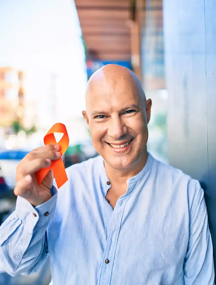 happy bald man holding orange cancer prevention research trust ribbon